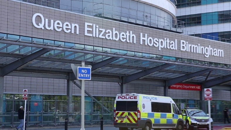 Exterior of Queen Elizabeth Hospital Birmingham with A&E entrance and police vehicle