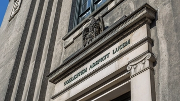 Neoclassical building entrance with a Latin inscription and stone eagle above the cornice